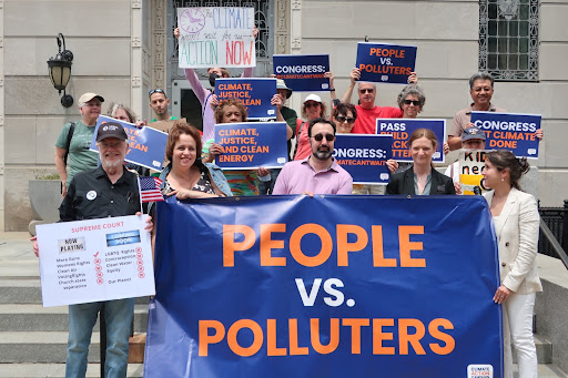 Photograph of climate activists holding signs and a banner reading "PEOPLE VS POLLUTERS"