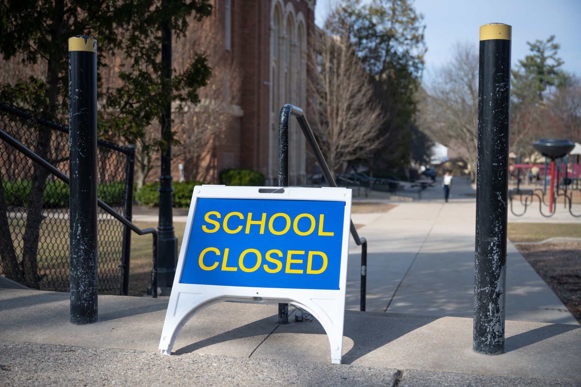 White & Blue sandwich board with "SCHOOL CLOSED" outside a school building